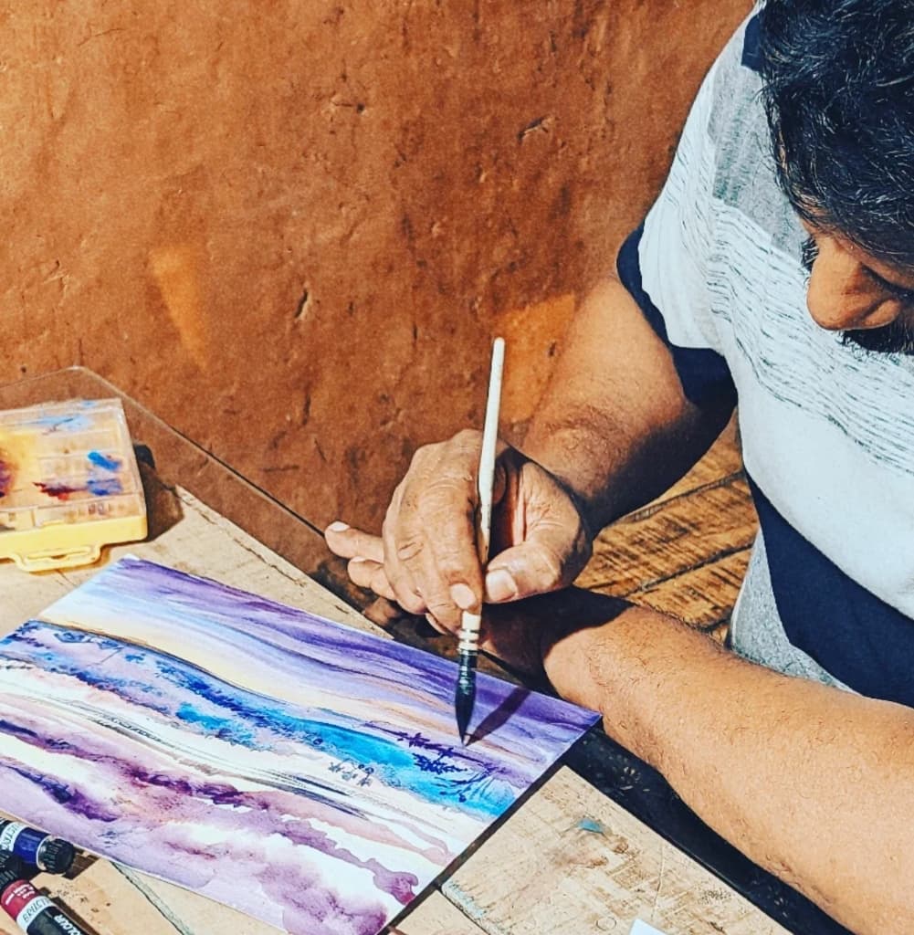 Resident artist painting a vibrant watercolor landscape of Kerala