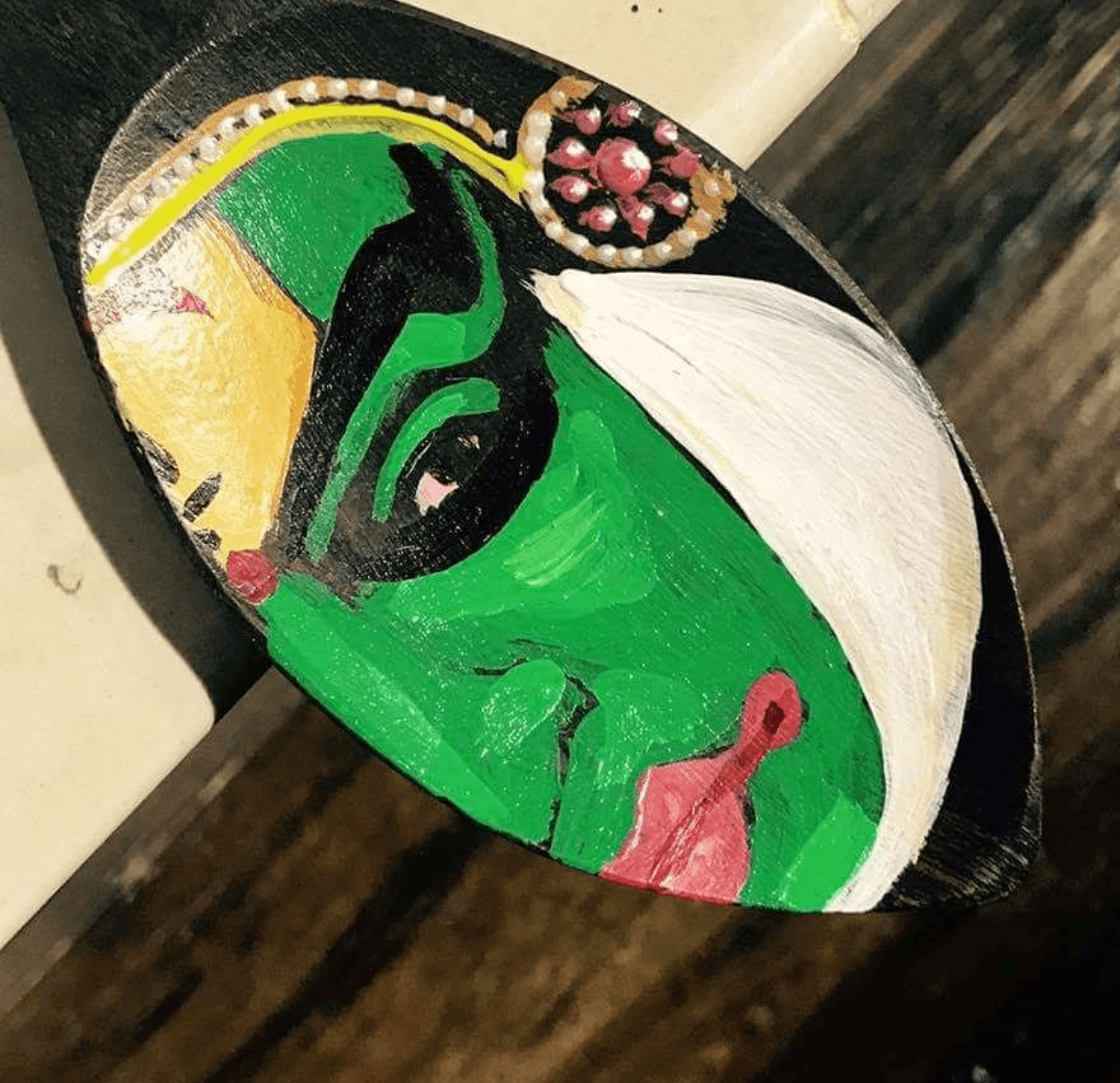 Hand-painted green Kathakali facial art on carved wooden spoon