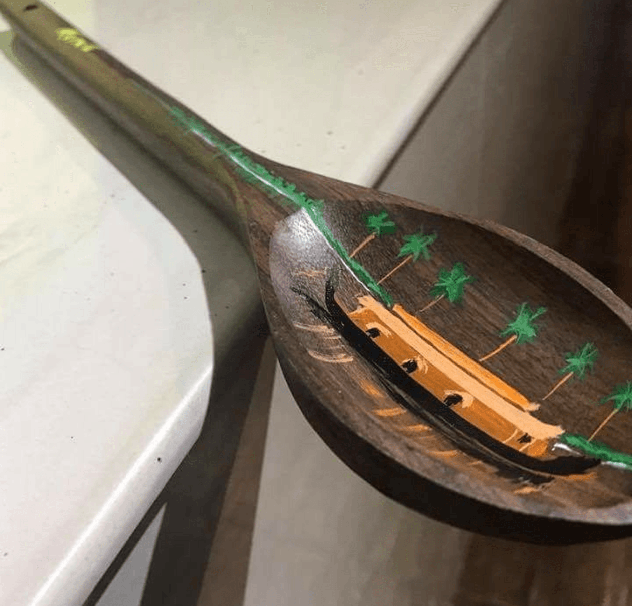 Hand-carved wooden spoon hand-painted with traditional Kerala houses and palm trees